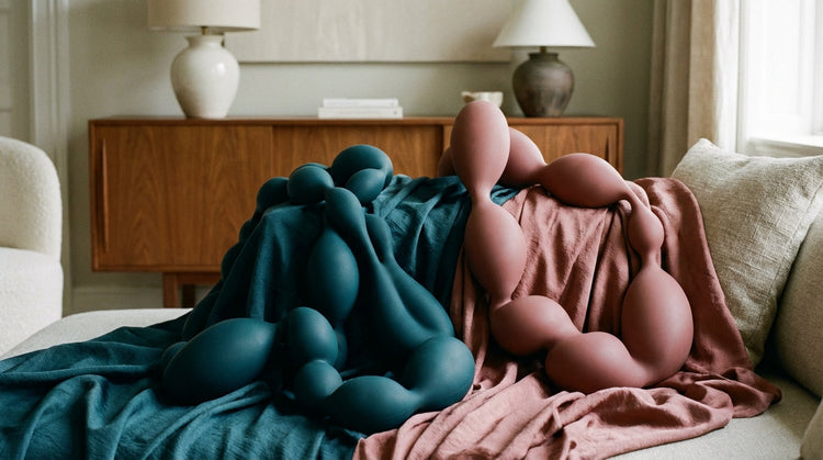 Abstract flowy shapes resembling smooth silicone beads, soft lighting with silk fabric textures, color palette of deep teal and dusty rose, professional interior photography style.