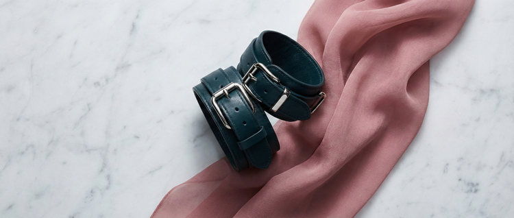 Premium bondage accessories including soft cuffs, blindfolds, and restraints, styled in a luxury bedroom setting for safe intimate exploration.