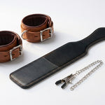 Leather cuffs and paddle with chain on a white background
