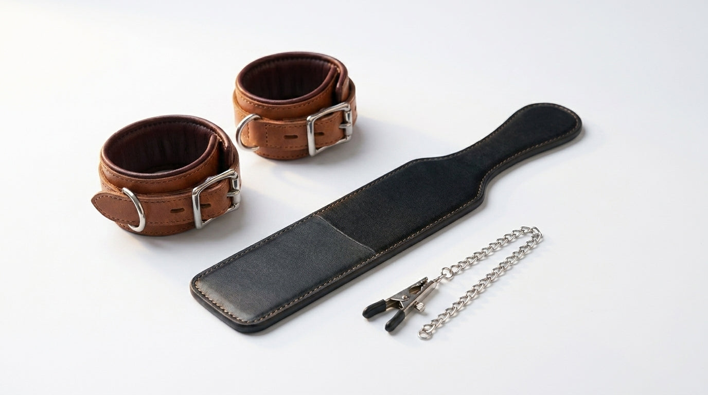 Leather cuffs and paddle with chain on a white background
