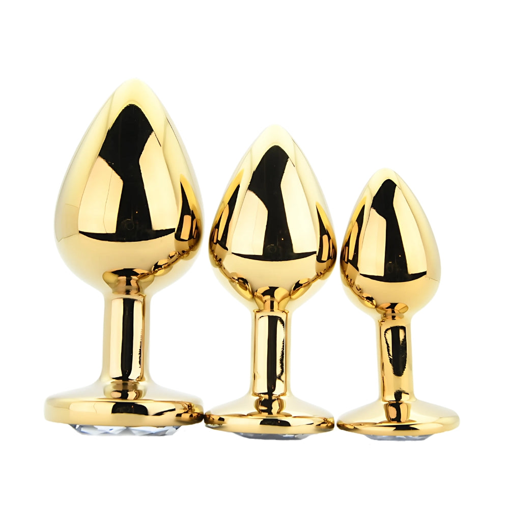 Three gold metallic butt plugs of different sizes on a white background